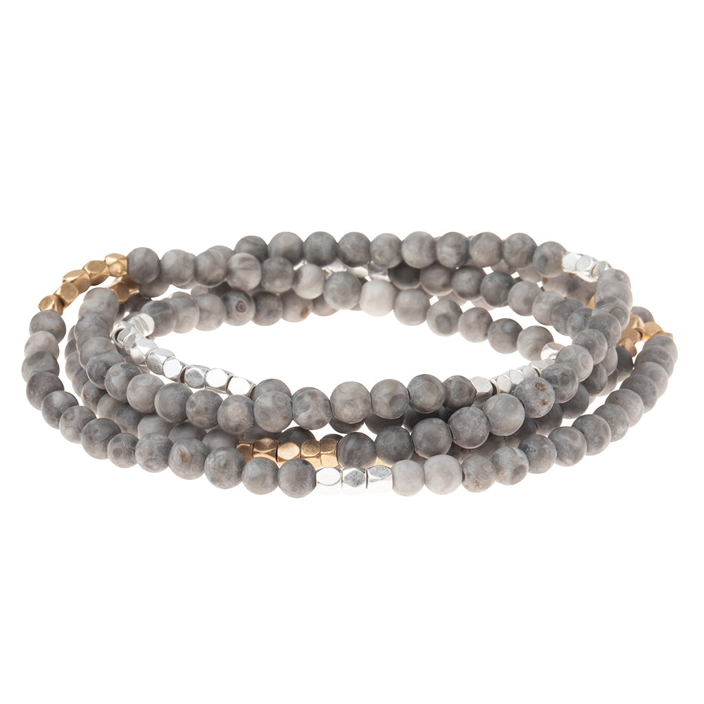 4.5 millimeter riverstone beads interspersed with gold and silver beads wrapped four times to form a bracelet, shown on a white background.
