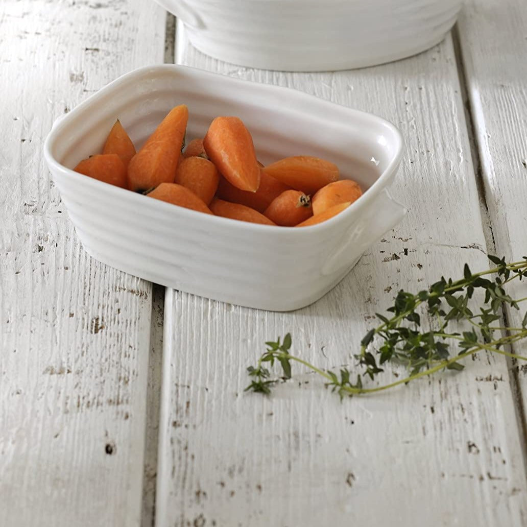 small roasting dish filled with carrots on a white wood slat table.