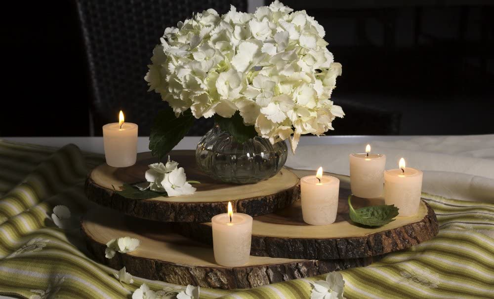 three sizes of the acacia wood slab boards displayed with a flower arrangement and candles on a green striped tablecloth