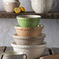 stack of bowls on wood table with other bowls on the background.
