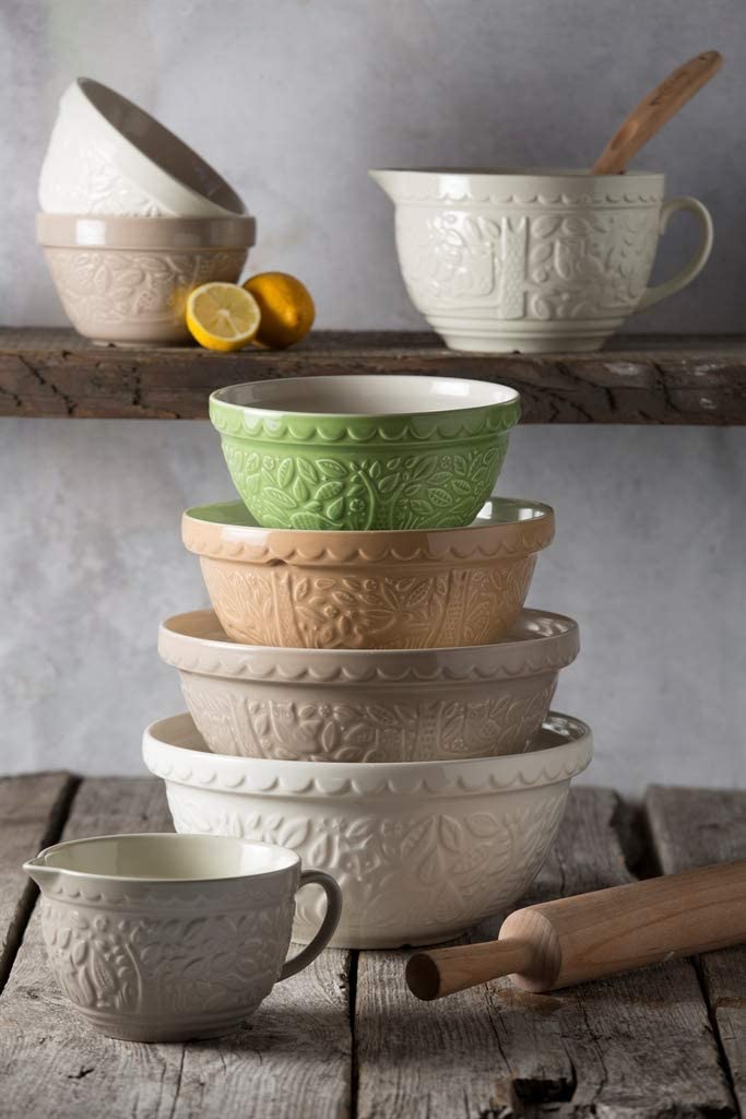 mixing bowls stacked on wooden table with additional bowls on background.