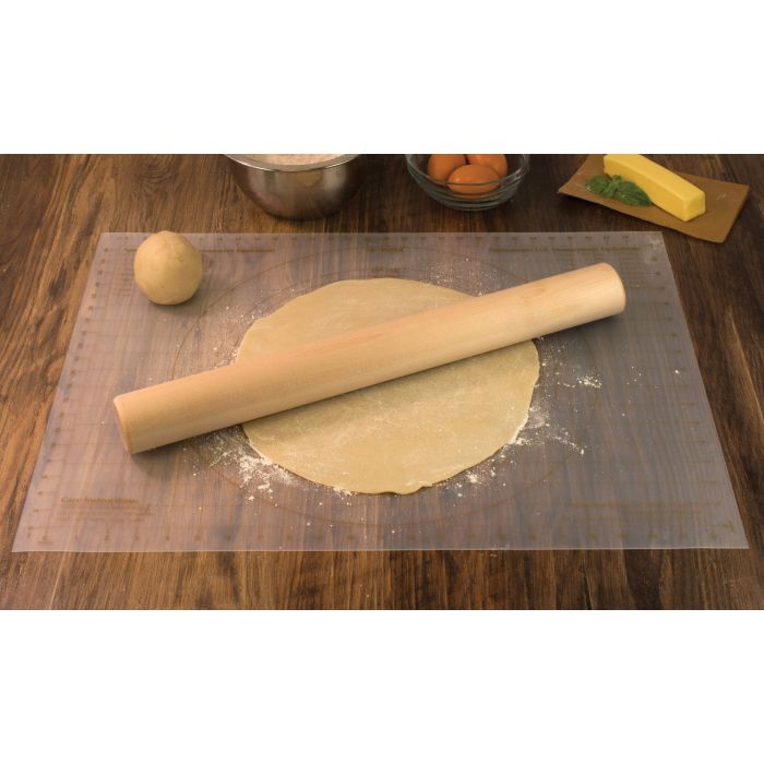the bakers rolling pin displayed on a rolled pastry on a dark stained wood surface beside a bowl of eggs stick of butter and bowl of flour
