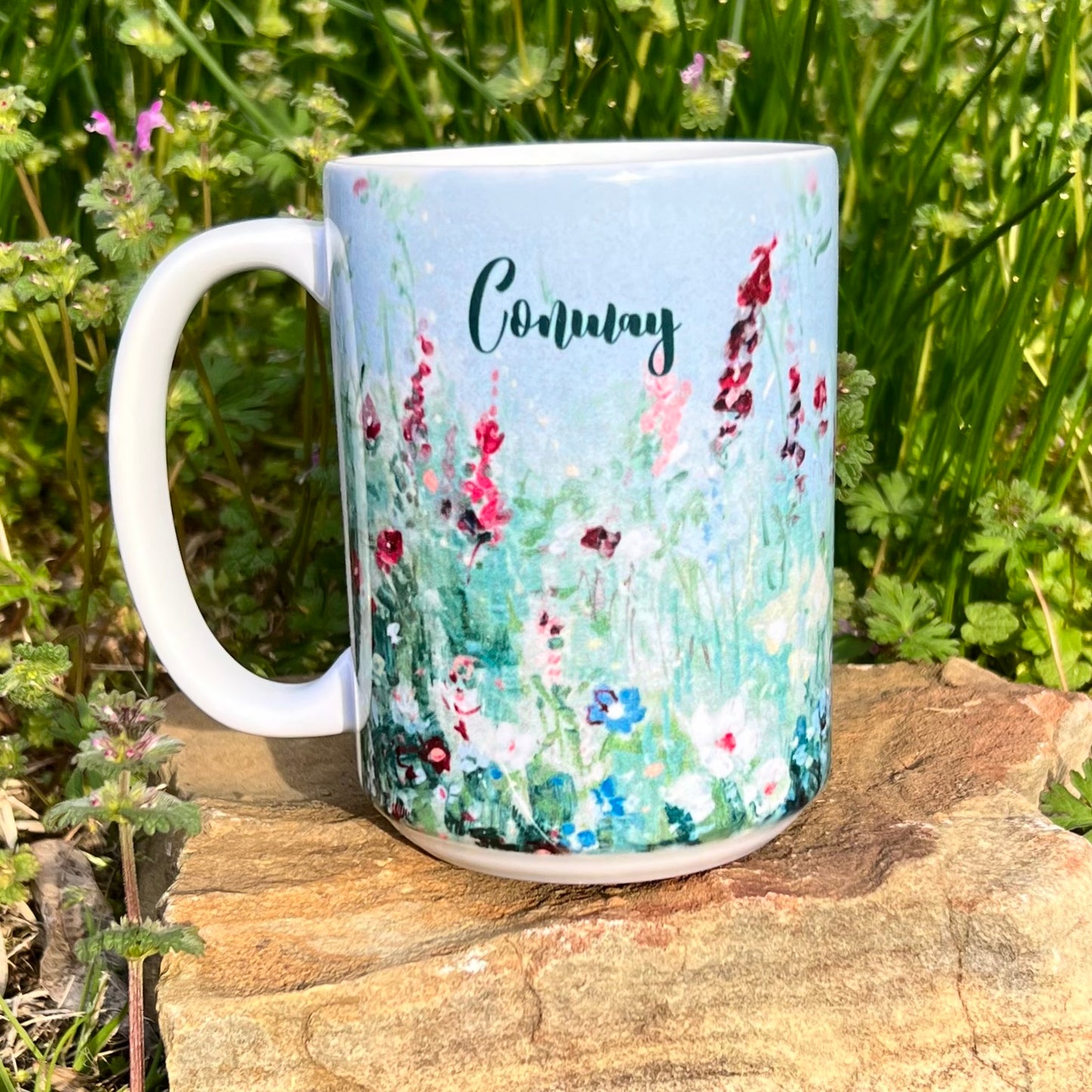 blue mug with wildflower design and "conway" printed on it.