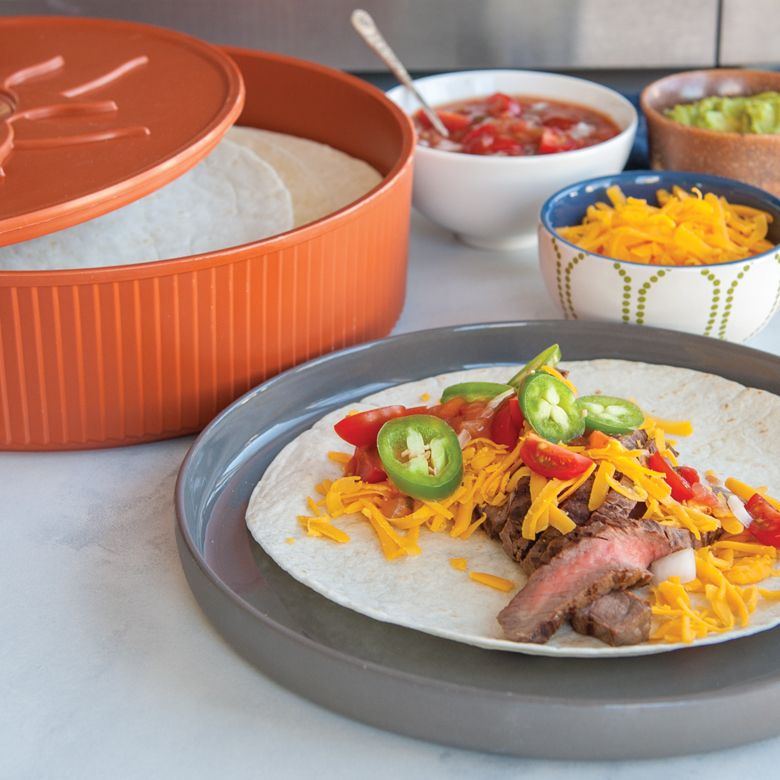 table set with fajita toppings and tortillas in warmer.