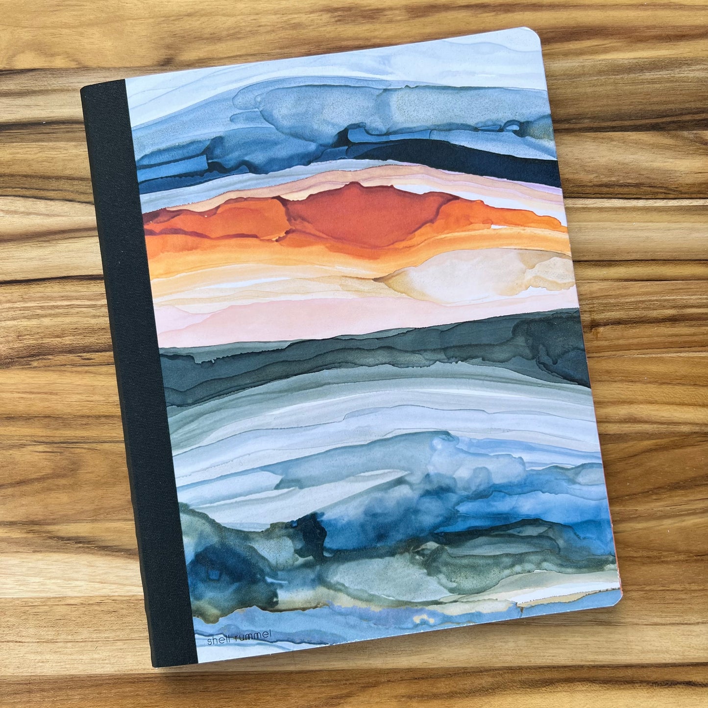 notebook with abstract sunrise design printed on the cover.