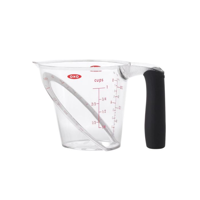 measuring cup with black handle, red markings, and angle rim inside.