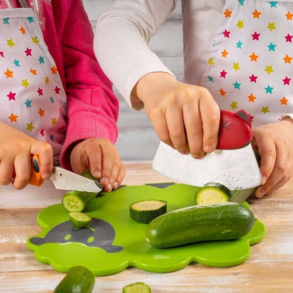 children's hand using cat and dog knives to chop veggies on a lamb shaped cutting board.