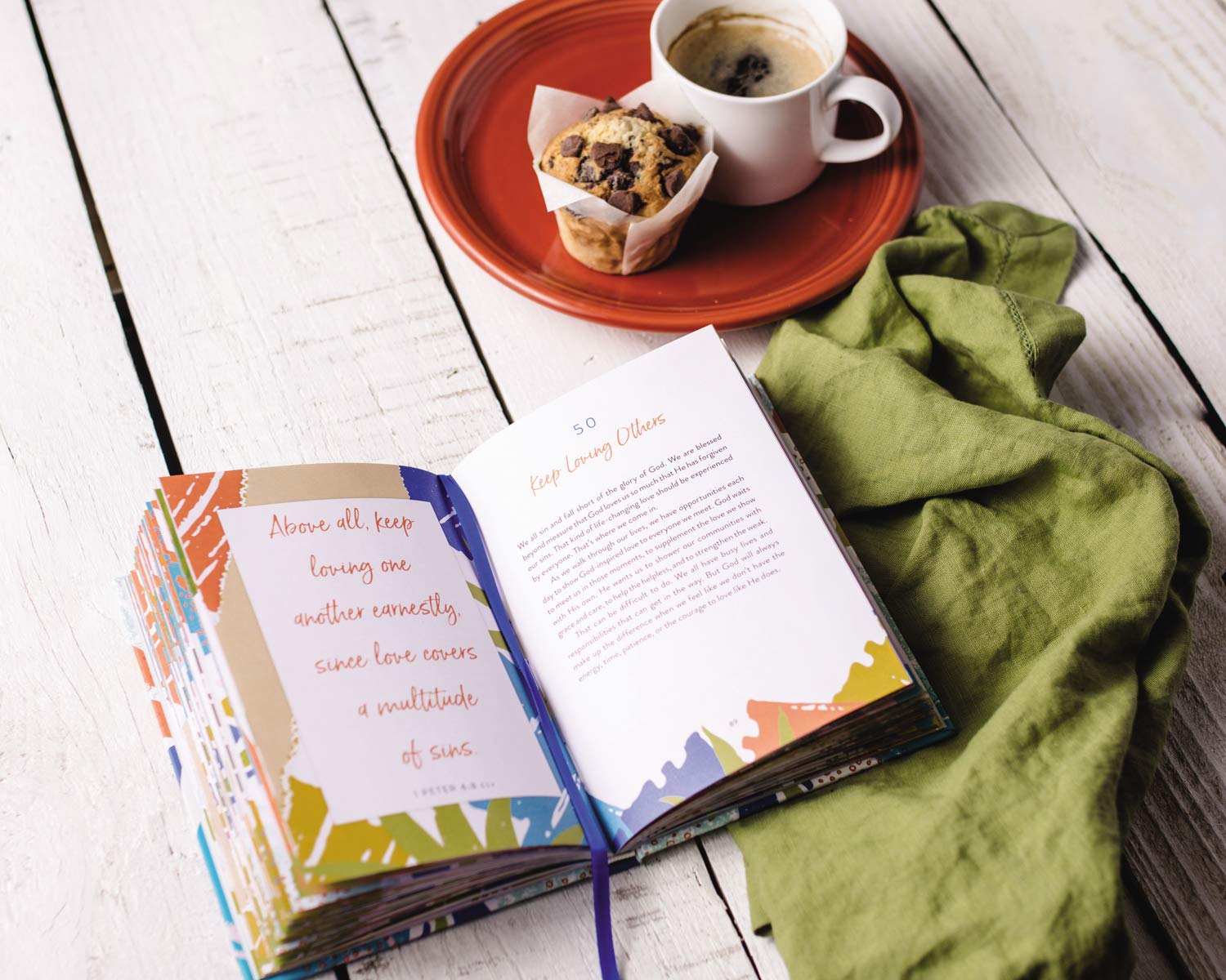 book open to show inside pages are brightly colored beside a plate with food