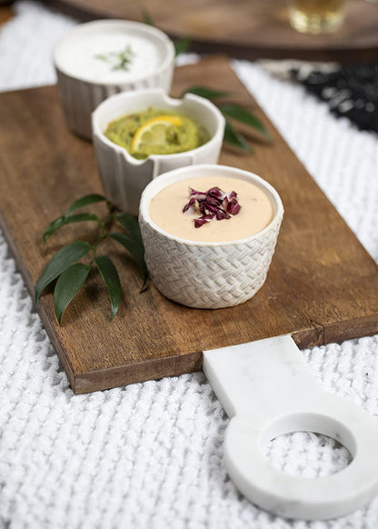textured ramekin set filled with dip and displayed on a wooden serving board