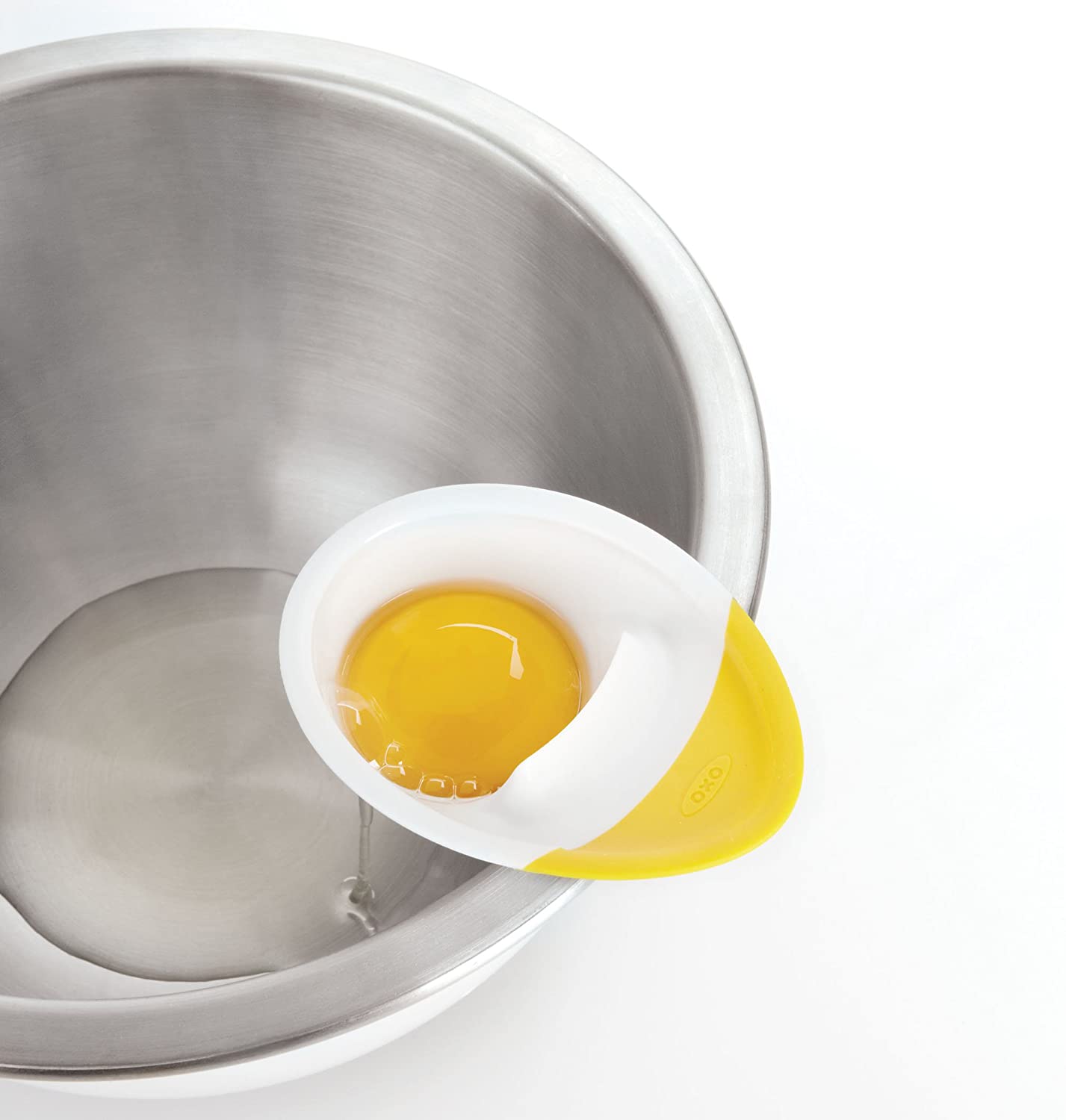 egg separator with yolk in it on bowl edge.