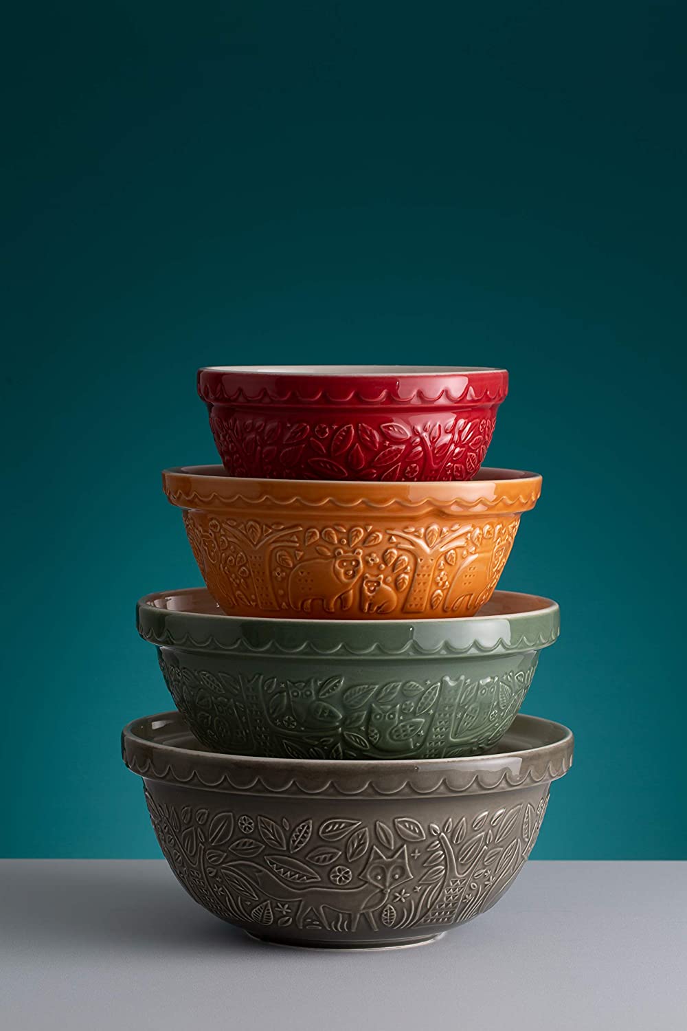 stack of mixing bowls on grey counter with teal background.