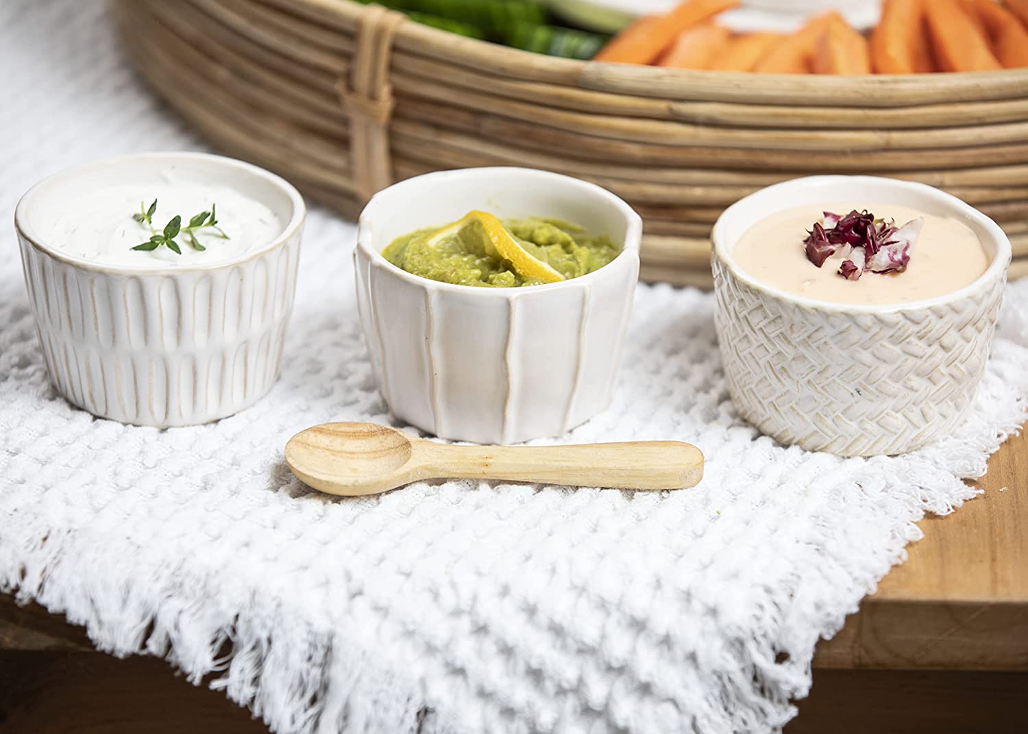 all three textured ramekins filled with dip and displayed next to a veggie tray on a white table runner