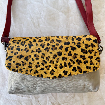 rounded grey purse with brown and black cheetah print flap and red strap.