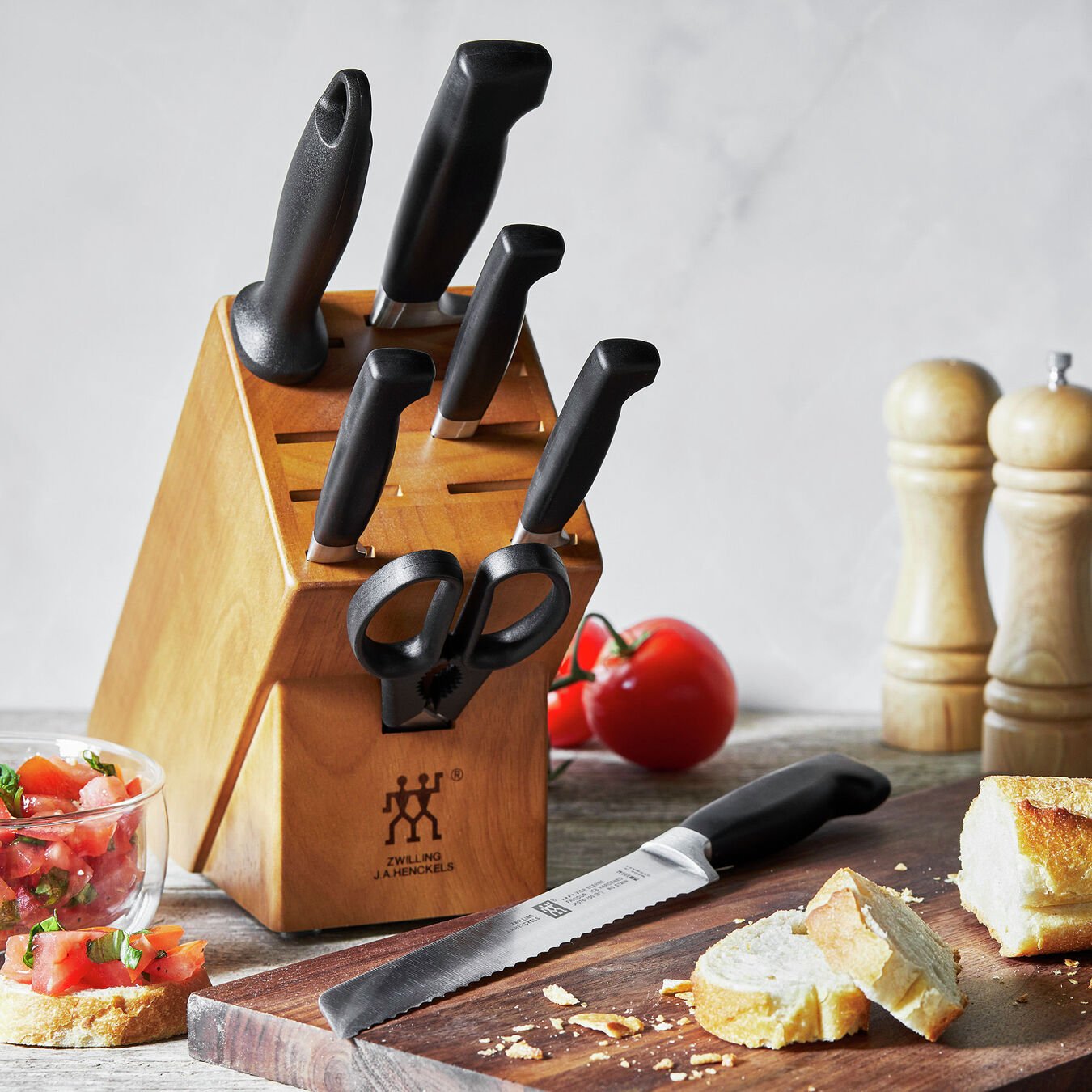 knife block in kitchen scene with cutting board, salt and pepper grinder, and sliced bread and tomatoes