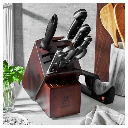 knife block with knives and sharpener on a kitchen countertop with herbs and a utensil crock.