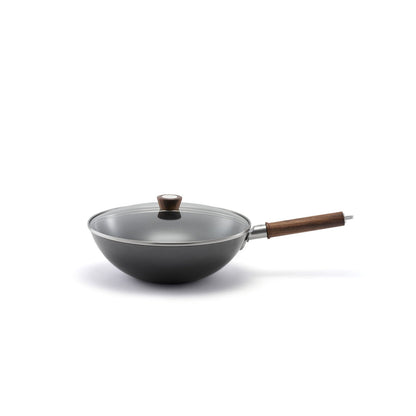 matte black carbon steel wok with glass lid and walnut handle on white background