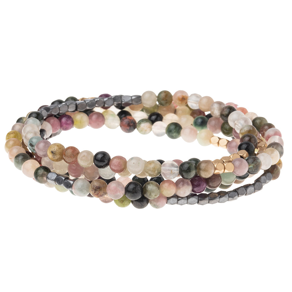 4.5 millimeter tourmaline hematite beads interspersed with gold and silver beads wrapped four times to form a bracelet, shown on a white background.