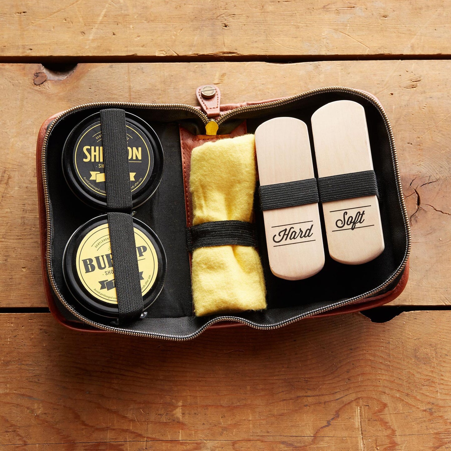 the shoe shine kit displayed in the open case on wood planks