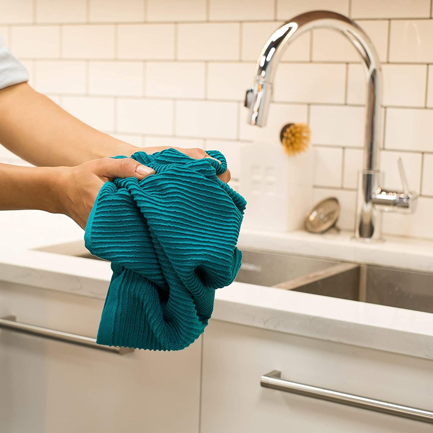 hands holding dishtowel at kitchen sink.