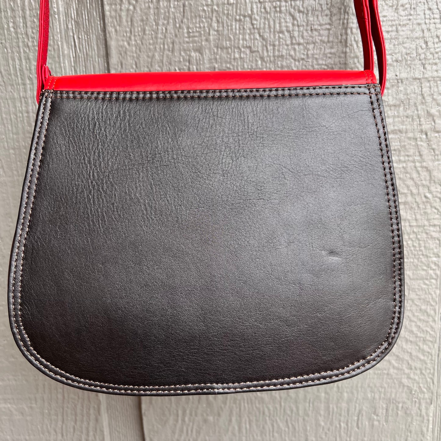 solid black back of purse with red strap.
