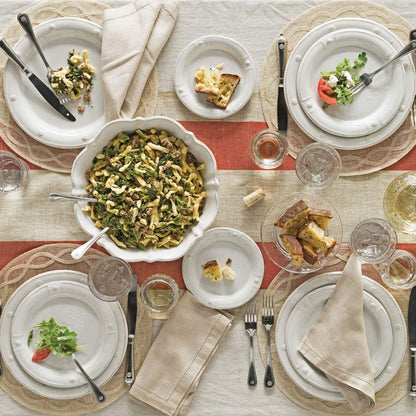 table setting with dinner plates, salad plates, serving bowl, glasses, and flatware on a linen table cloth