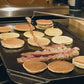illustration of pancakes and bacon being turned with the pig tail grilling food flipper on a kitchen stove