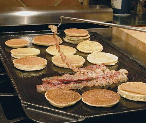 illustration of pancakes and bacon being turned with the pig tail grilling food flipper on a kitchen stove