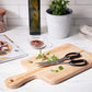 take apart kitchen shears displayed on a cutting board with cut spices next to a potted spice plant, bottle of oil and towel on a white countertop