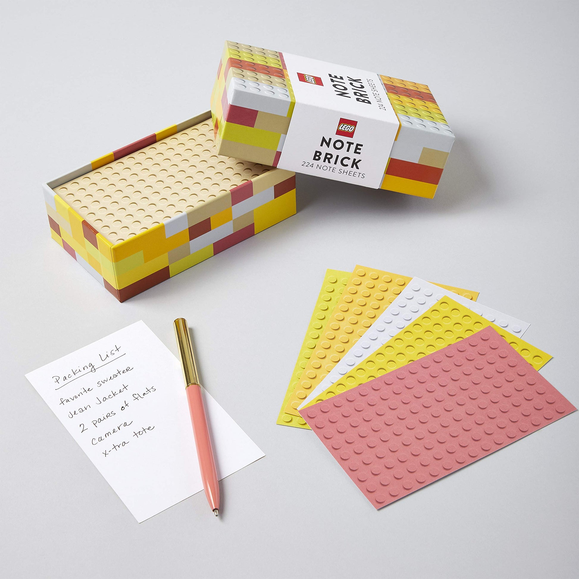 lego designed box with lid off-set to show note paper inside and sheets of note paper with lego design fanned out with a pen.
