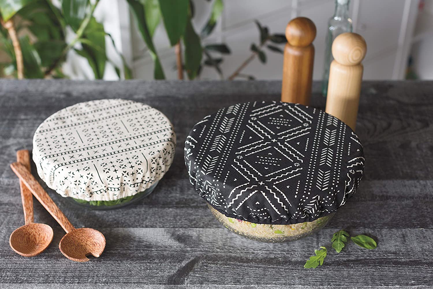 bowl covers on bowls; one black with white design, the other white with black design.