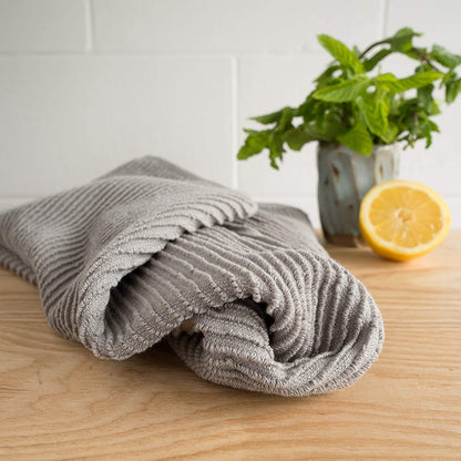 dishtowel laying on counter with lemon and plant.