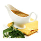 gravy boat filled with gravy set on a napkin with fresh herbs.