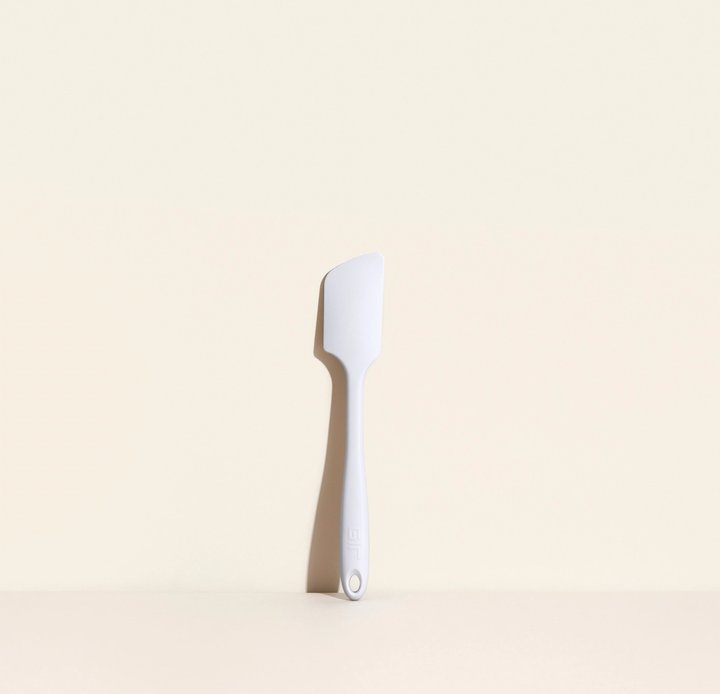 ultimate spatula leaning against a cream colored background.