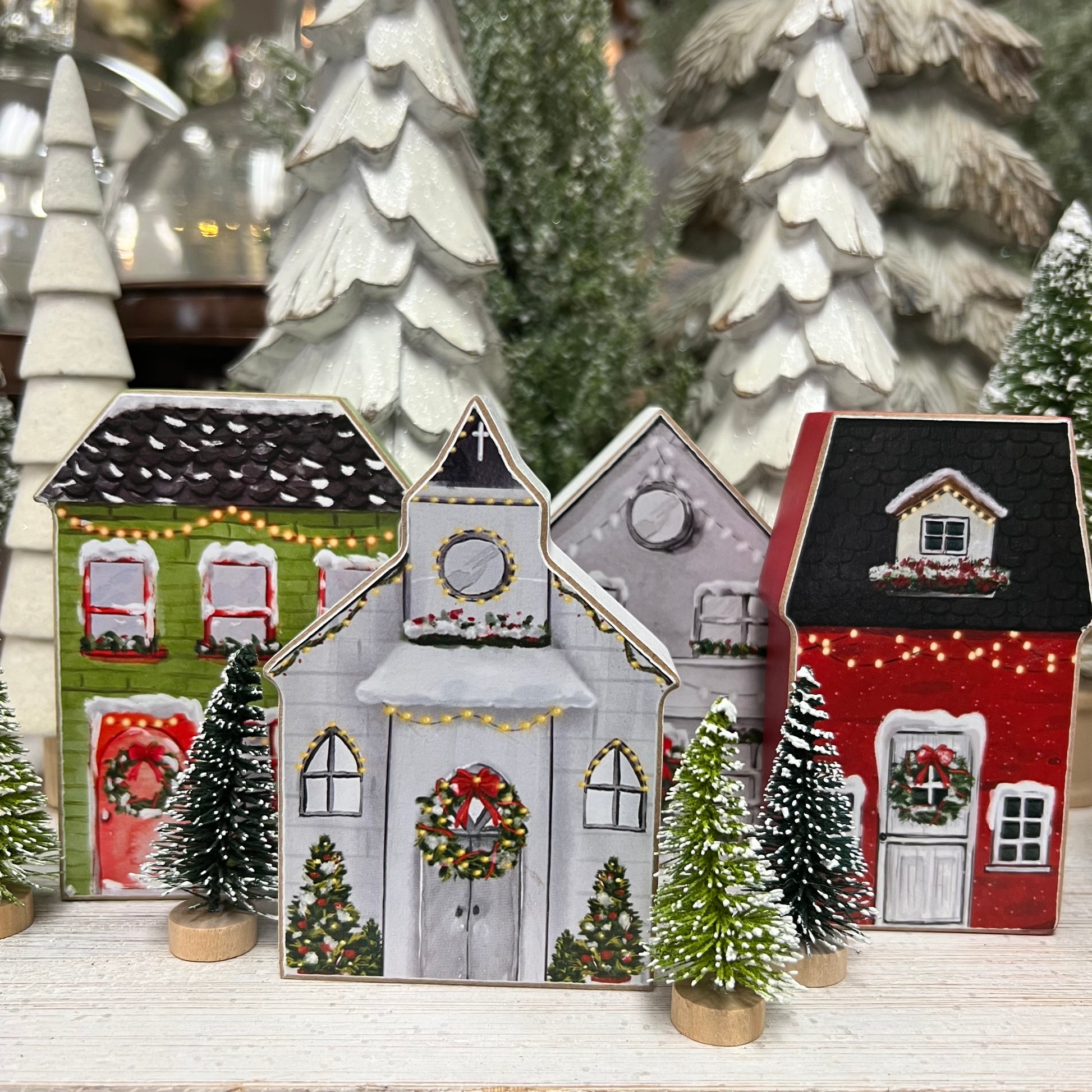 wood block houses and a church set on a wooden shelf with small trees.