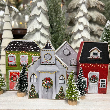 wood block houses and a church set on a wooden shelf with small trees.