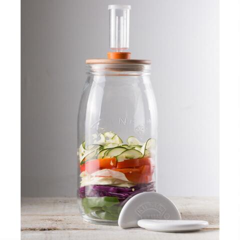 glass jar half full of vegetables on a wooden countertop.