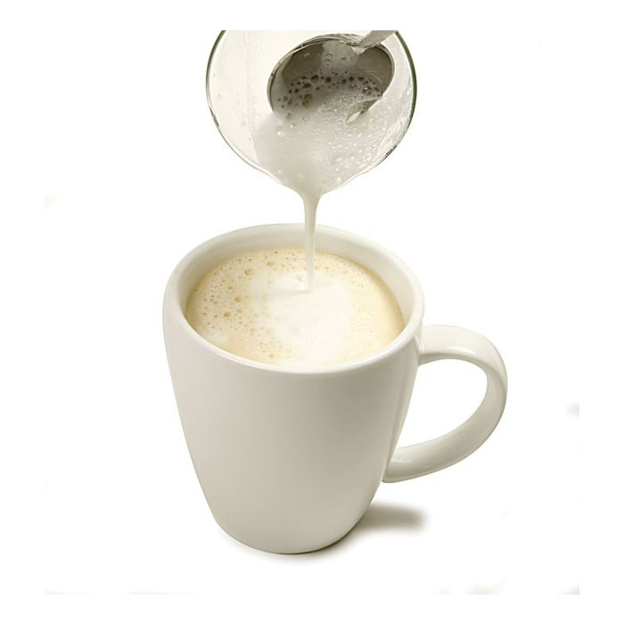 spoon putting frothed milk on to coffee in a mug.