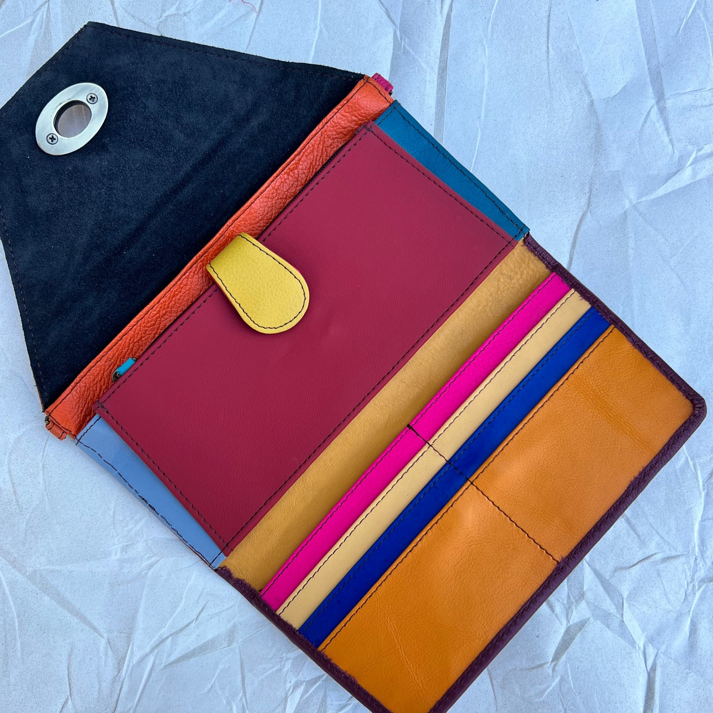 open view of the maroon and mango secret clutch revealing bright colors of fuchsia, yellow, tan, maroon, and blue 
