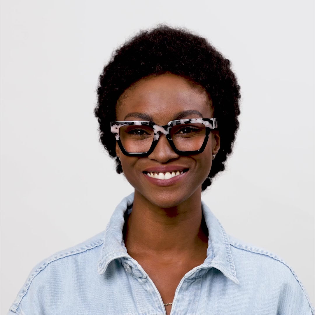video of a woman modeling the black marble and black take a bow glasses and turning her head to show both sides against a cream background 