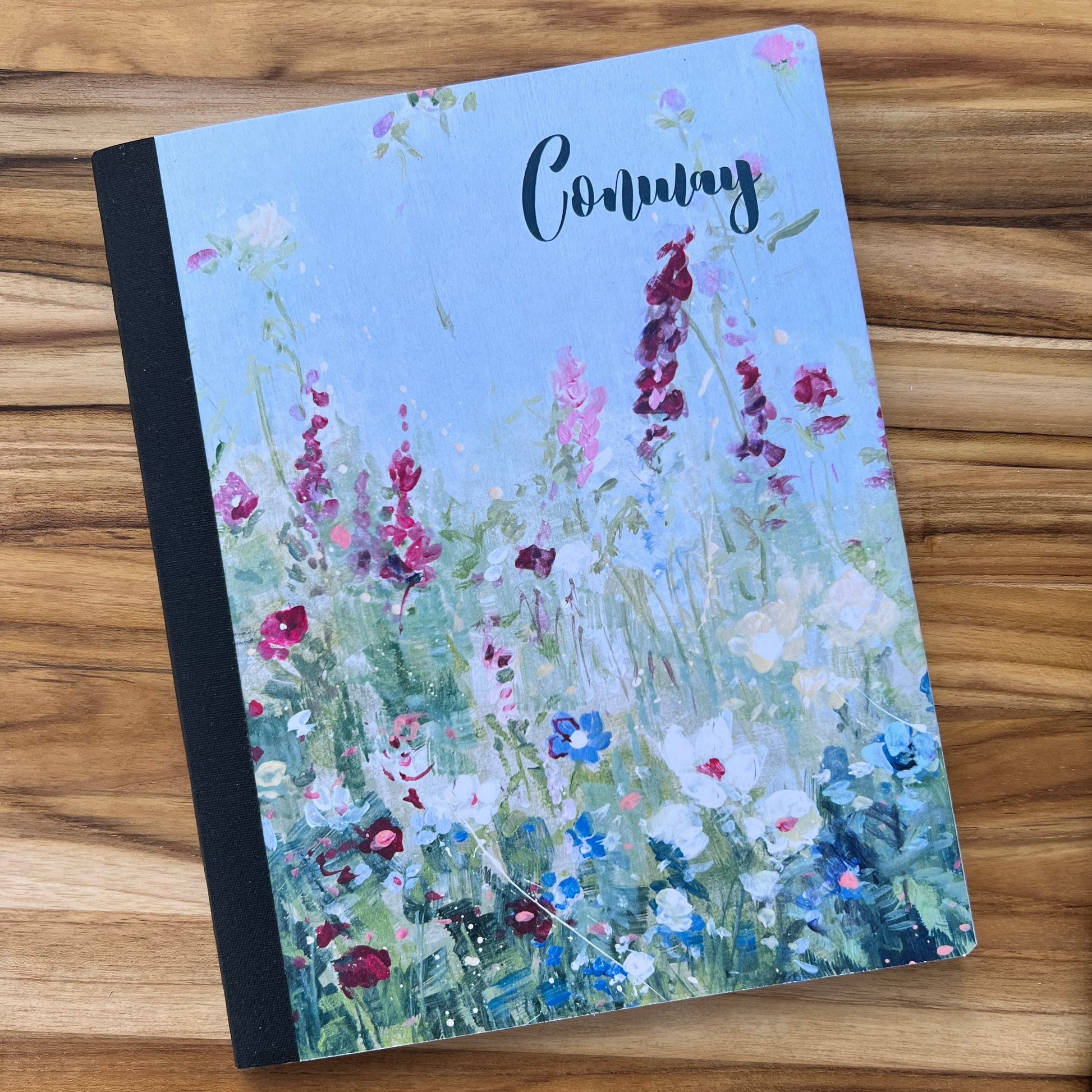 blue notebook with wildflowers design and "conway" printed on the cover.