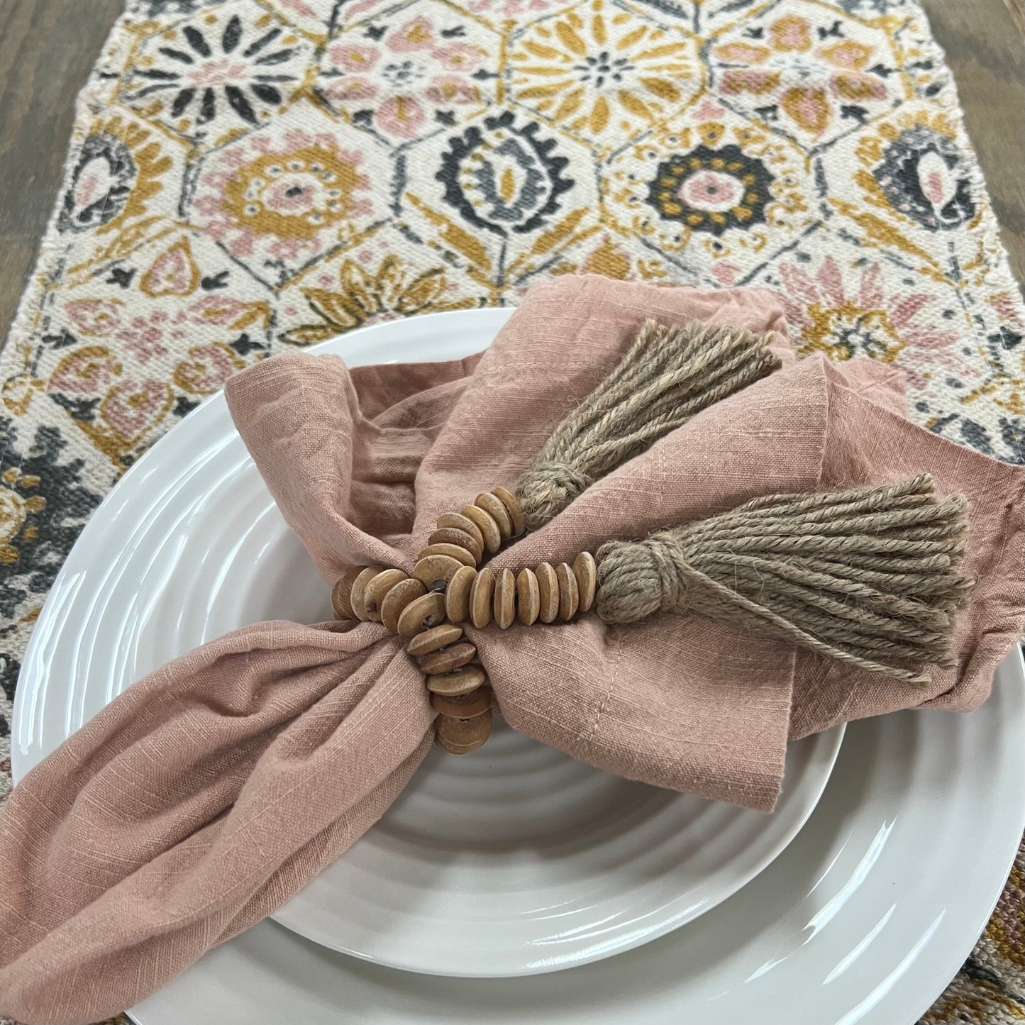 top view of table with runner, white dishes, and blush napkin.