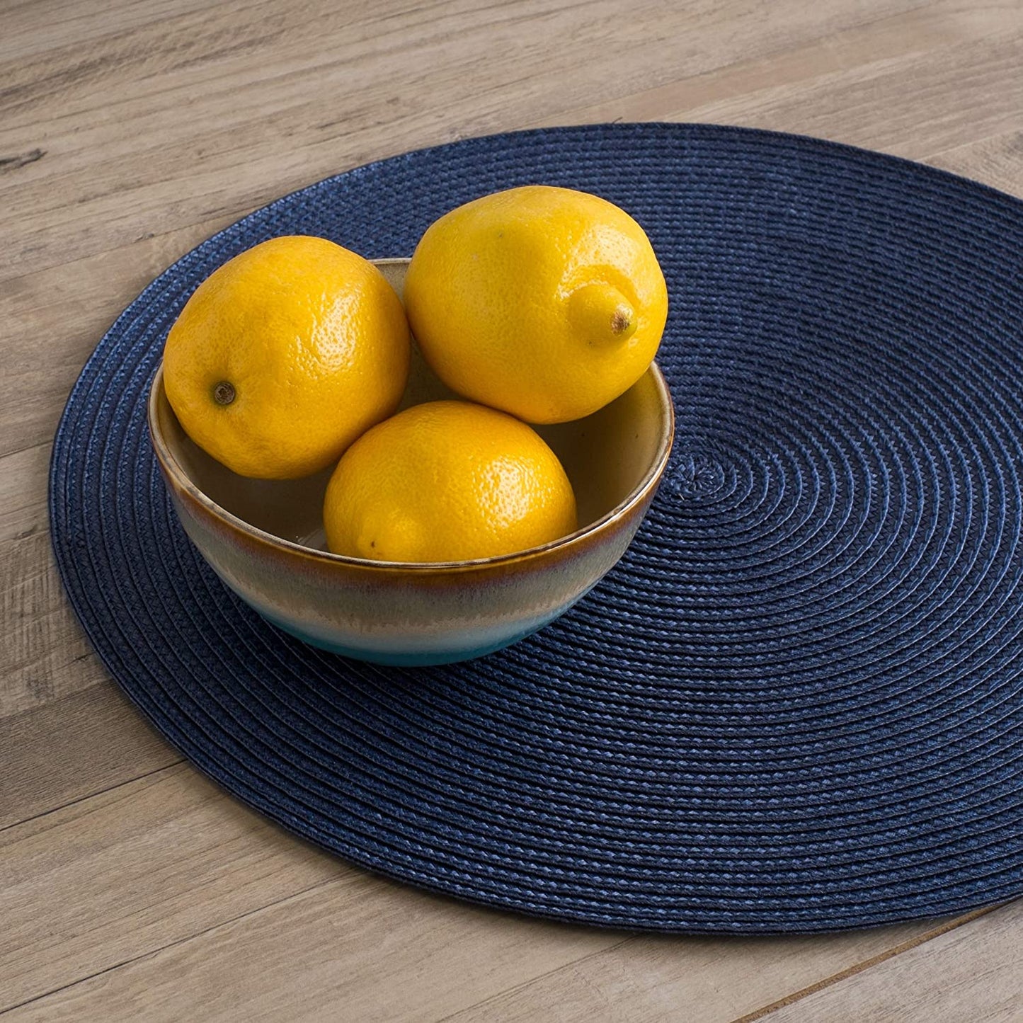 blue placemat with bowl of lemons on it.