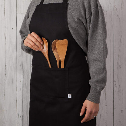 person wearing apron with wooden utensils in pocket.