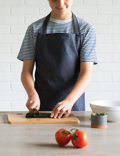 child wearing apron while slicing veggies.