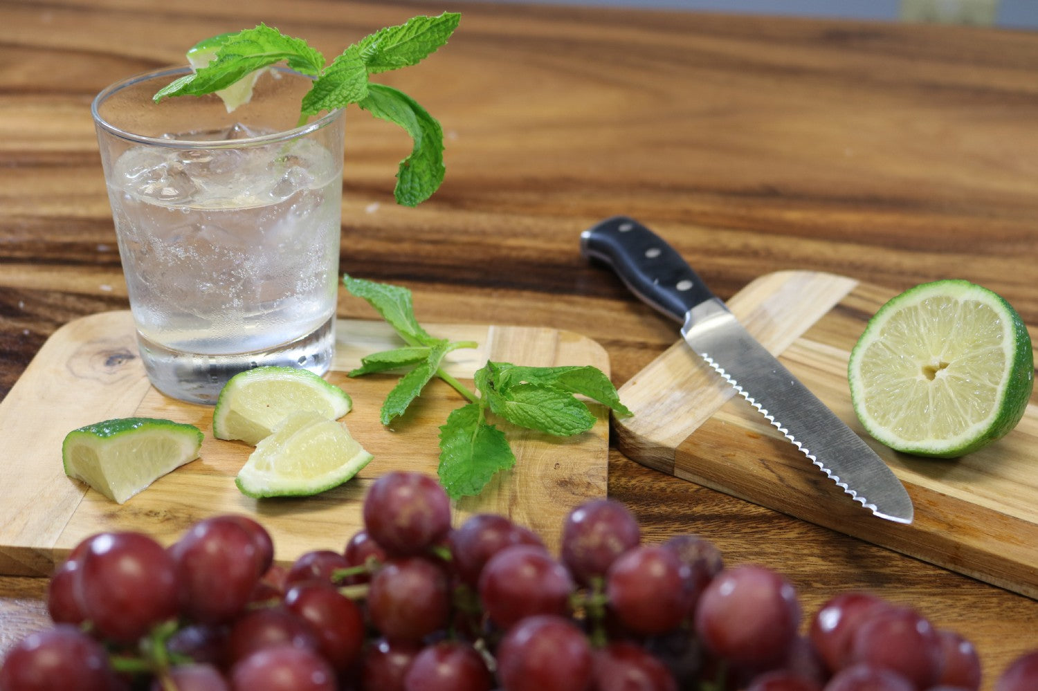 2 bamboo boards arranged with a beverage, lime slices and grapes.