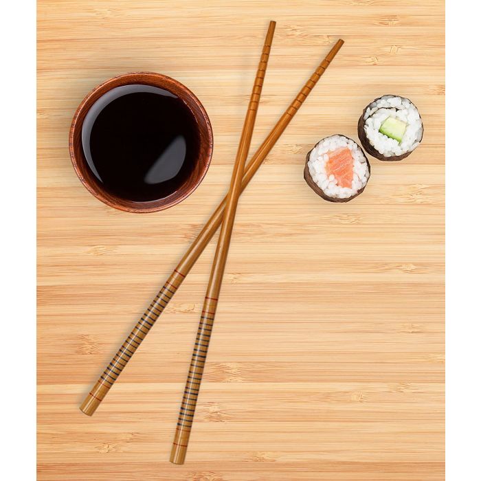 a pair of silk wrapped chopsticks displayed next to sushi and a bowl of soy sauce on a wooden surface