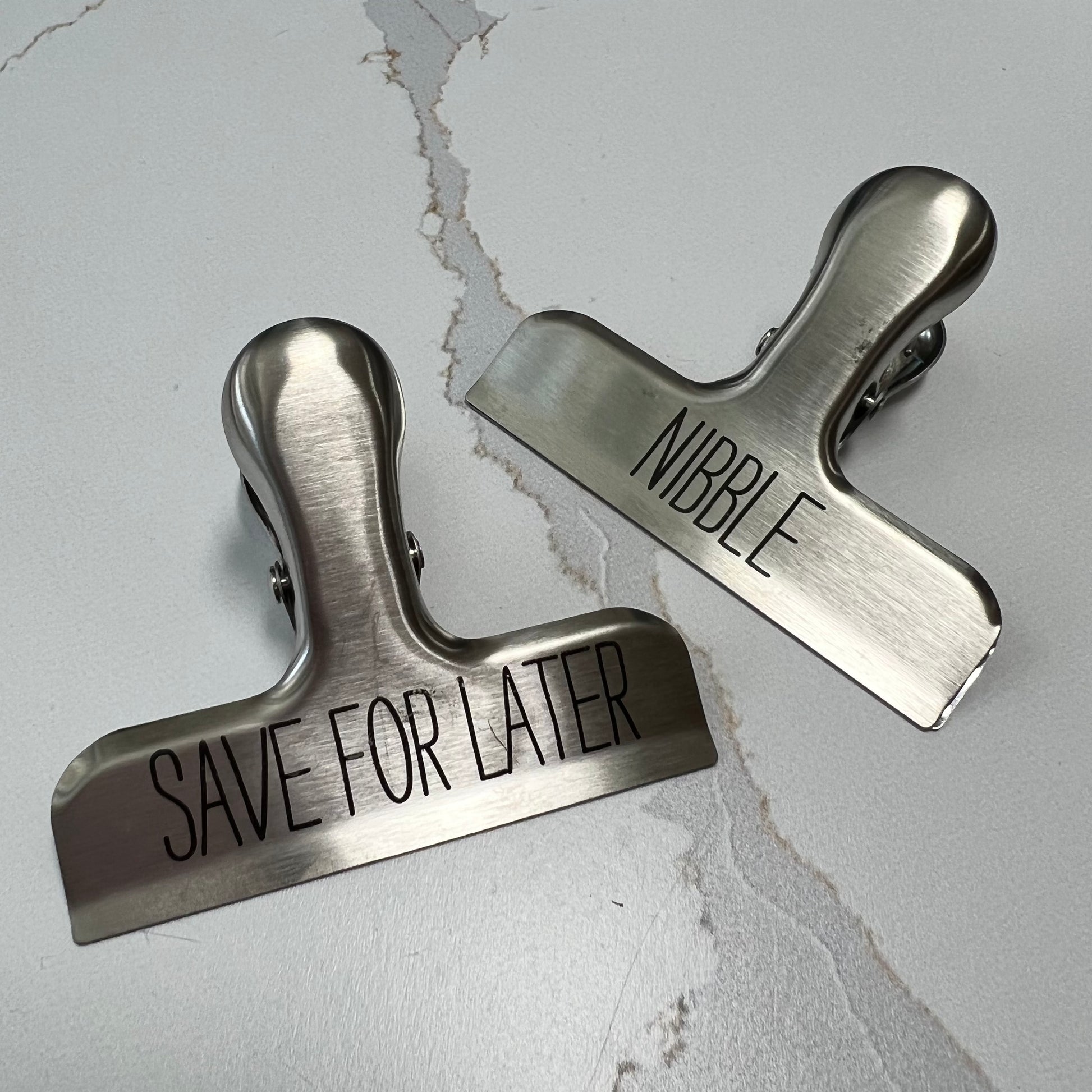 "save for later" and "nibble" bag clips on a white marble counter.