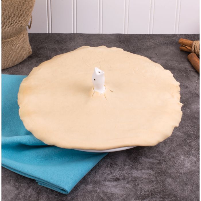 the pie bird vent displayed inside an uncooked pie sitting on a gray countertop with a towel