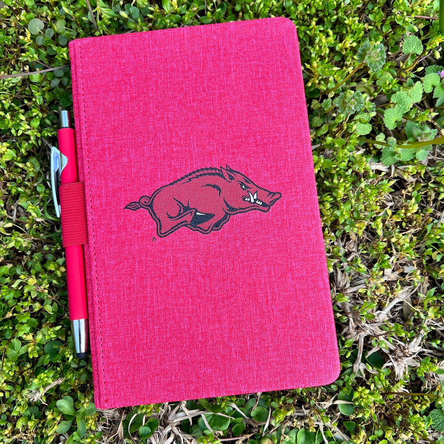 red journal with razorback logo in the center and red pen attached to the side with elastic loop.
