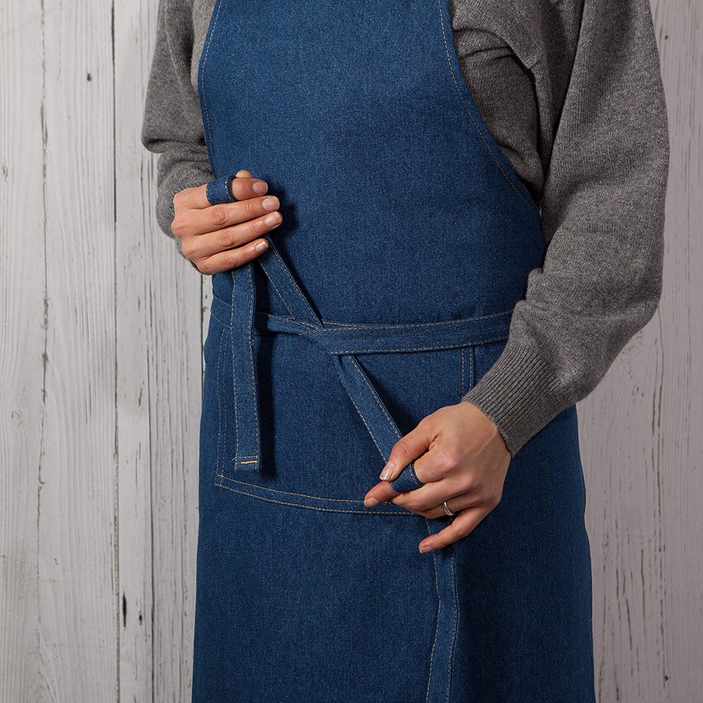 person wearing apron and tying it around their waist.